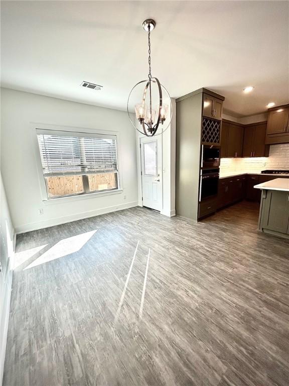 kitchen with dark brown cabinetry, visible vents, light countertops, tasteful backsplash, and dark wood finished floors