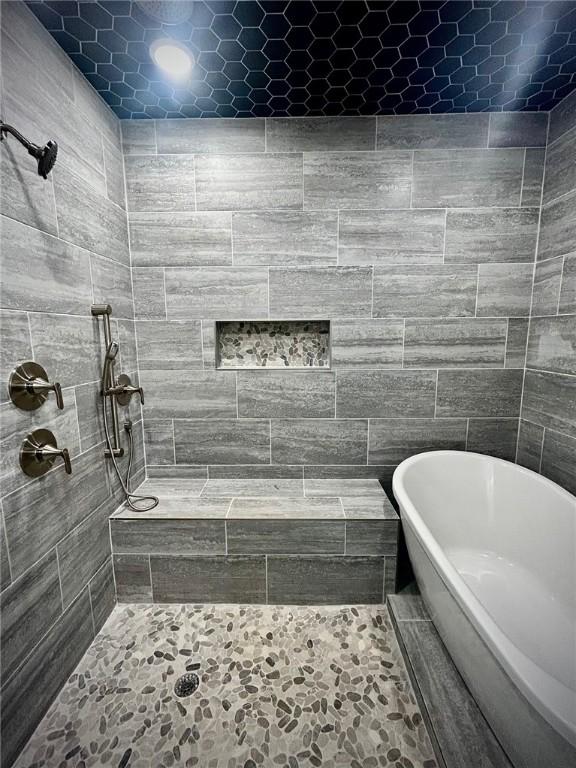 full bath featuring tiled shower and a freestanding bath