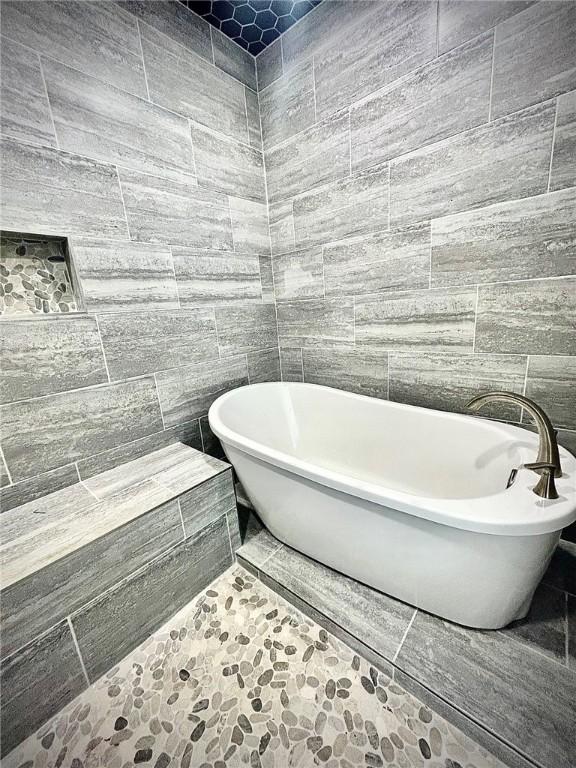 bathroom with a freestanding tub and tile walls