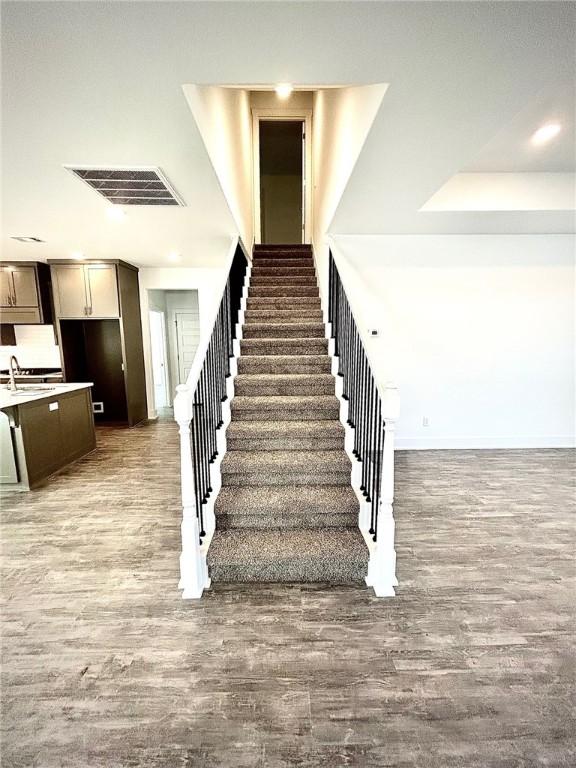 stairs featuring wood finished floors and visible vents