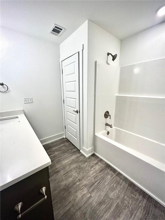 full bathroom with baseboards, visible vents, wood finished floors, bathtub / shower combination, and vanity