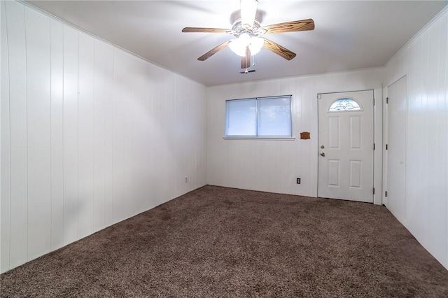 entryway featuring carpet, ceiling fan, and wood walls