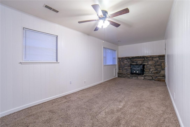 unfurnished living room with ceiling fan, carpet floors, and a wood stove