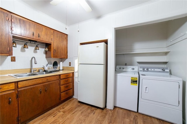 kitchen with sink, washer and clothes dryer, light wood-type flooring, ornamental molding, and white refrigerator