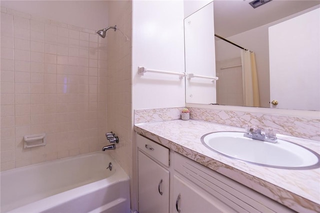 bathroom with tiled shower / bath combo and vanity