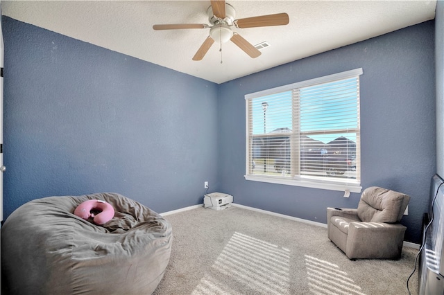 sitting room with a textured ceiling, ceiling fan, and light carpet