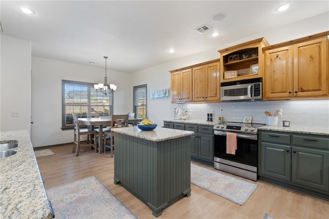 kitchen featuring light stone countertops, appliances with stainless steel finishes, light wood-type flooring, an inviting chandelier, and a kitchen island