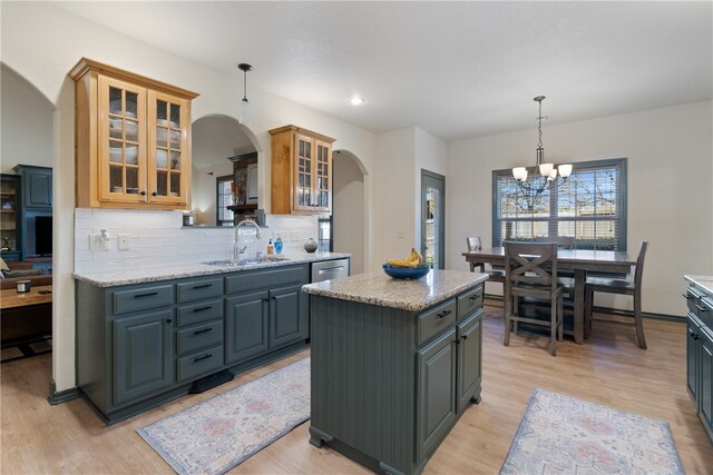 kitchen featuring a kitchen island, light stone countertops, light hardwood / wood-style floors, and sink