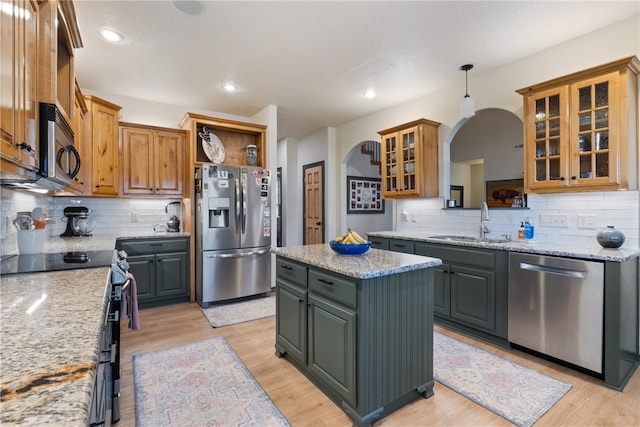 kitchen featuring decorative backsplash, a kitchen island, light wood-type flooring, and stainless steel appliances