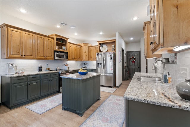 kitchen with light stone countertops, sink, a kitchen island, and stainless steel appliances