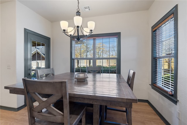 dining area featuring plenty of natural light, light wood-type flooring, and a chandelier