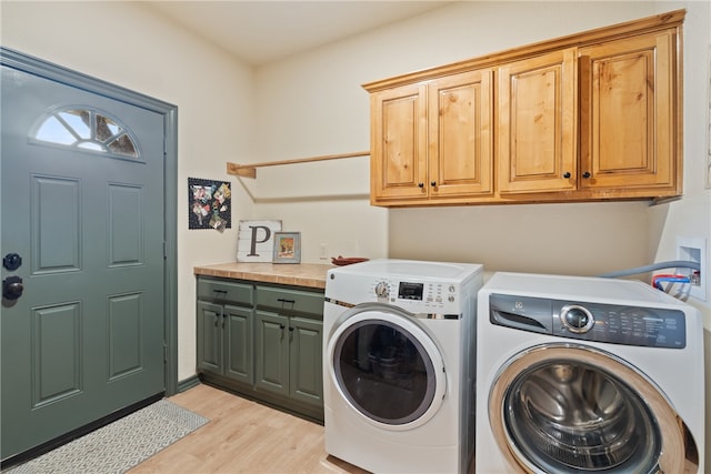 laundry room featuring washer and dryer, cabinets, and light hardwood / wood-style floors