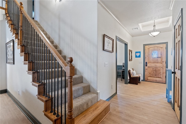 entrance foyer featuring a textured ceiling, light hardwood / wood-style flooring, and ornamental molding