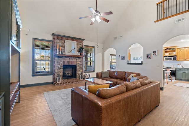 living room with plenty of natural light, a large fireplace, high vaulted ceiling, and light hardwood / wood-style flooring