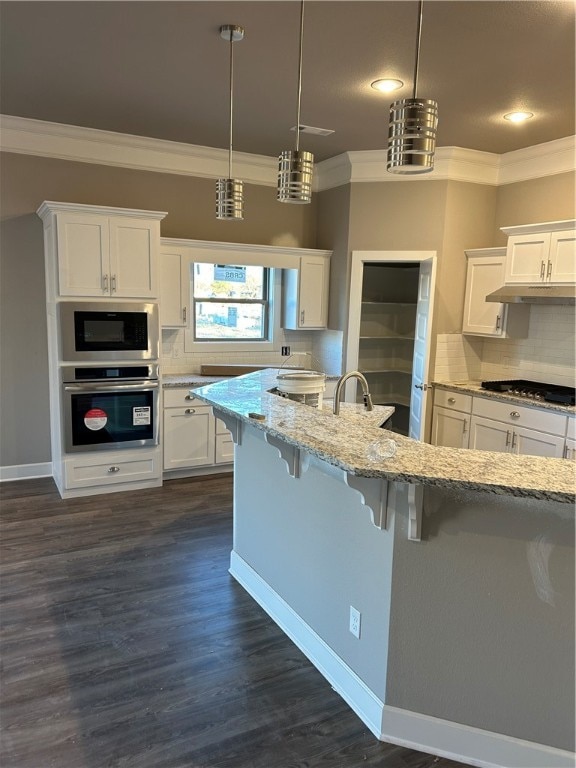 kitchen with a breakfast bar, hanging light fixtures, appliances with stainless steel finishes, dark hardwood / wood-style flooring, and white cabinetry