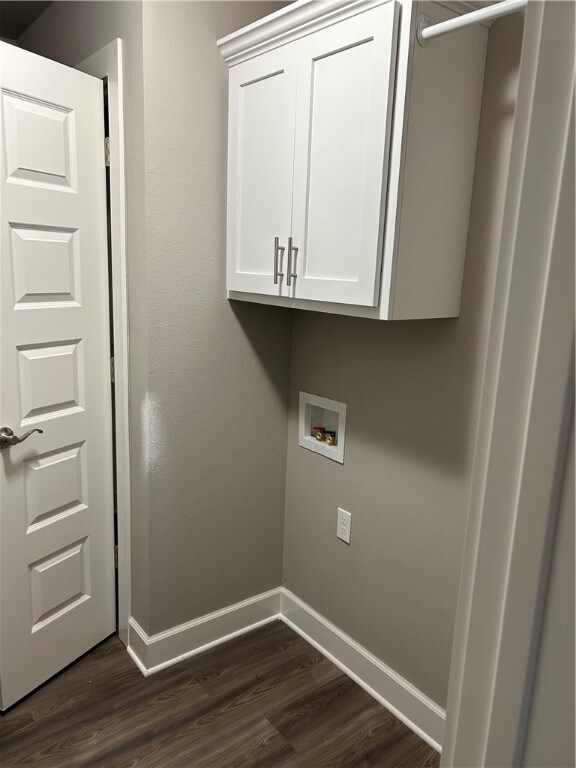 clothes washing area with hookup for a washing machine, dark hardwood / wood-style flooring, and cabinets