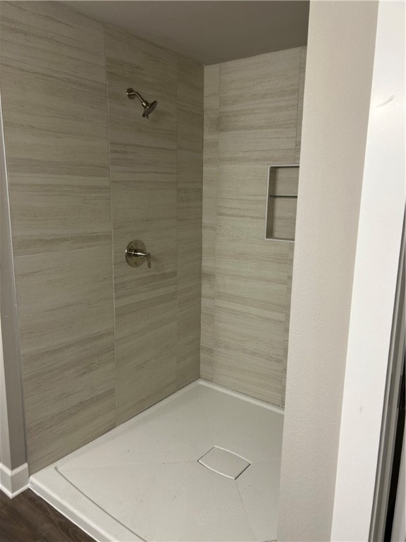 bathroom with hardwood / wood-style floors and tiled shower