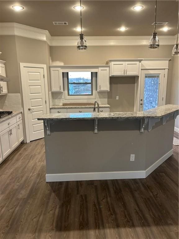 4833 W Planetree St, Fayetteville, AR 72704 - kitchen with crown molding, white cabinets, light stone counters, a kitchen breakfast bar, and dark wood-type flooring