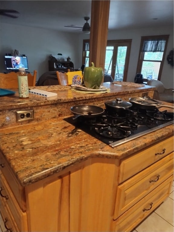 kitchen featuring ceiling fan, light stone countertops, light tile patterned floors, and black gas cooktop