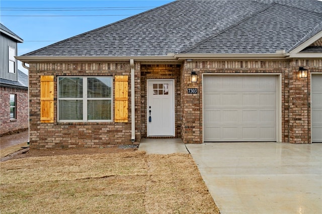 view of front of property with a shingled roof, a garage, brick siding, and concrete driveway