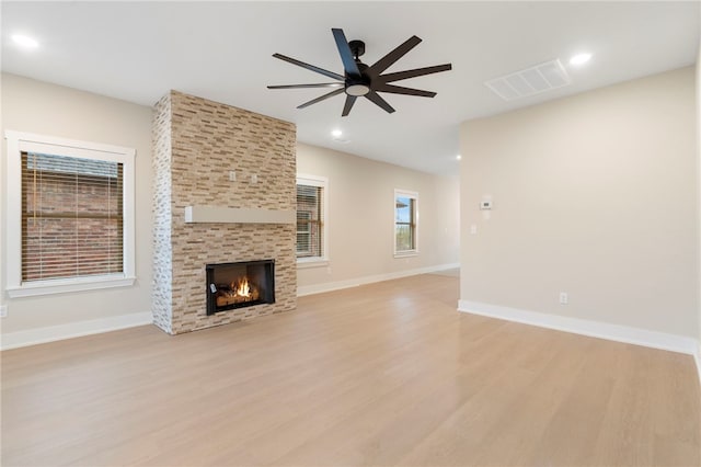 unfurnished living room with a fireplace, light wood-style floors, ceiling fan, and visible vents