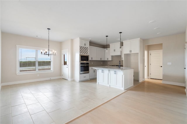kitchen featuring a chandelier, tasteful backsplash, appliances with stainless steel finishes, open floor plan, and white cabinets