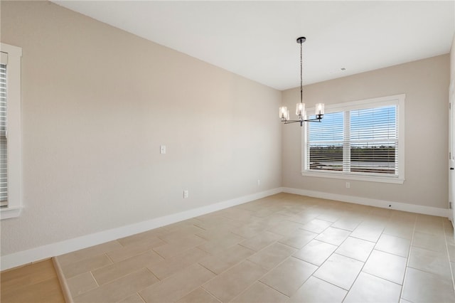spare room featuring baseboards and an inviting chandelier