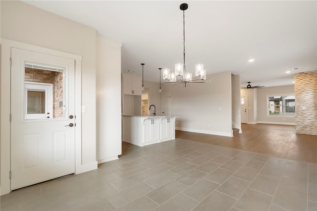 interior space with a sink, hanging light fixtures, open floor plan, ceiling fan with notable chandelier, and white cabinets