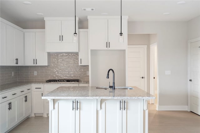 kitchen featuring a sink, tasteful backsplash, gas stovetop, a kitchen island with sink, and visible vents