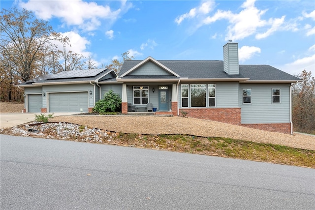 view of front of house with a garage, a porch, and solar panels