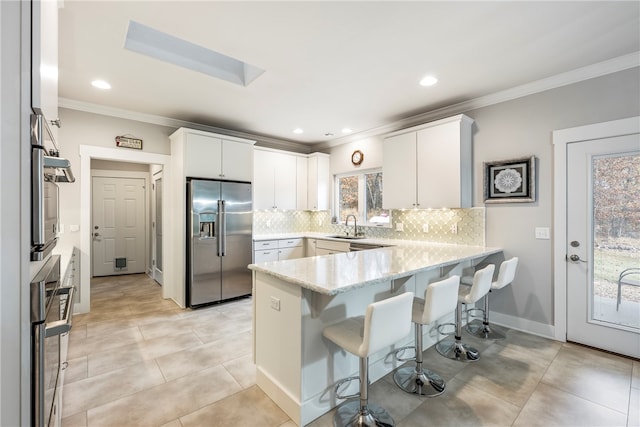 kitchen featuring tasteful backsplash, a breakfast bar, high end fridge, a peninsula, and a sink