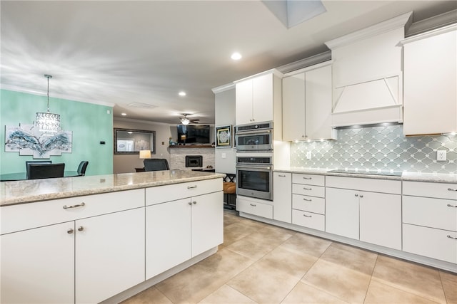 kitchen with decorative backsplash, black electric stovetop, premium range hood, pendant lighting, and white cabinets