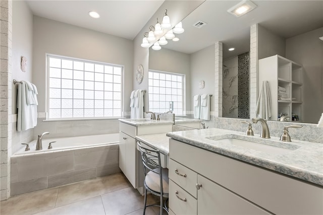 bathroom with tile patterned flooring, vanity, and a relaxing tiled tub