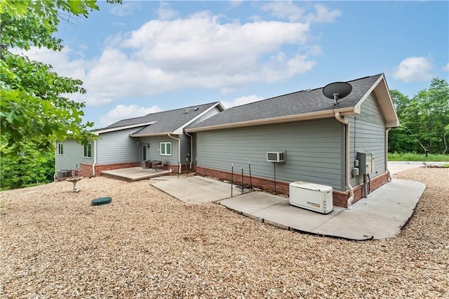 rear view of house with central AC, a shingled roof, a wall mounted AC, and a patio area