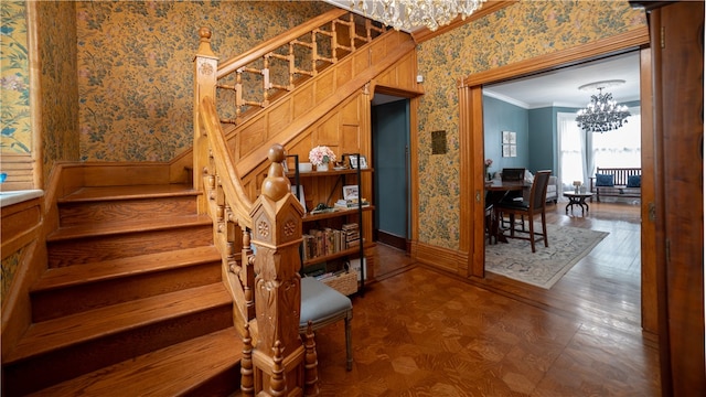 stairs with a notable chandelier and ornamental molding