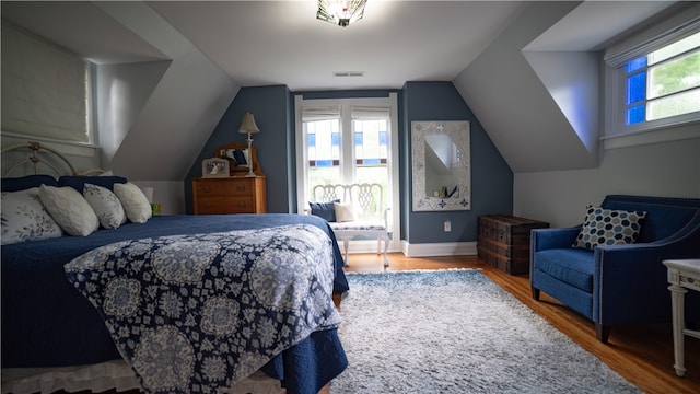 bedroom with hardwood / wood-style flooring, vaulted ceiling, and multiple windows