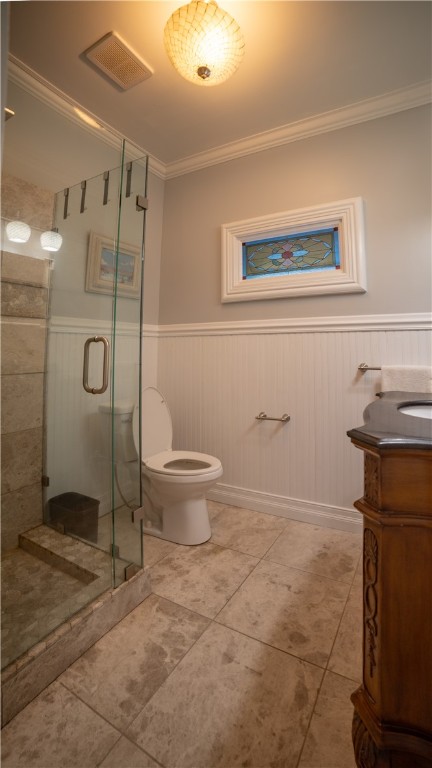 bathroom with tile patterned flooring, toilet, vanity, a shower with shower door, and ornamental molding