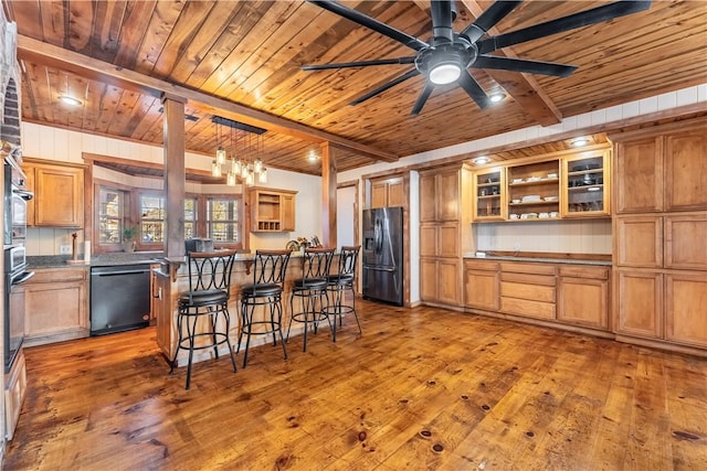 kitchen featuring beam ceiling, dishwasher, pendant lighting, a breakfast bar area, and black fridge with ice dispenser