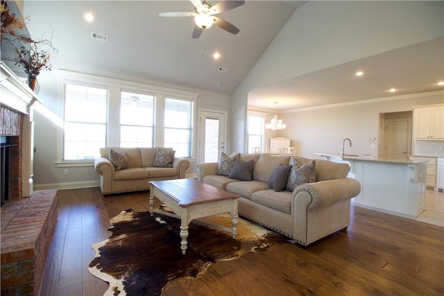 living room featuring high vaulted ceiling, ceiling fan with notable chandelier, ornamental molding, a fireplace, and dark hardwood / wood-style flooring