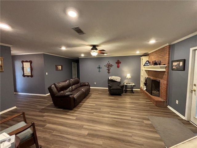 living room with ceiling fan, wood-type flooring, a fireplace, and ornamental molding