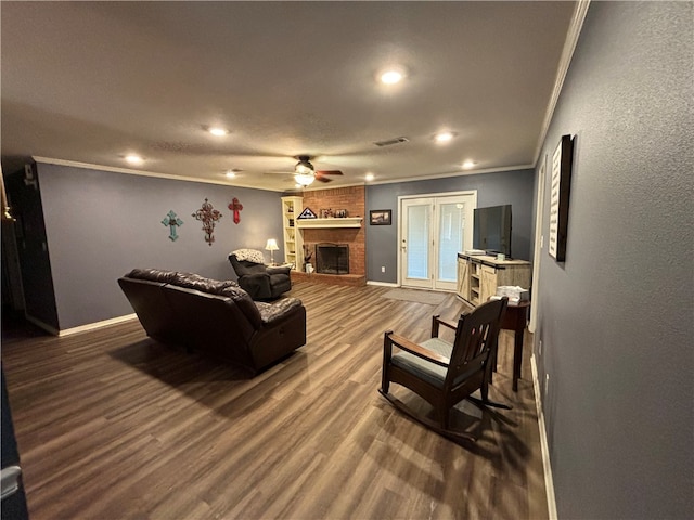 living room with a fireplace, ceiling fan, crown molding, and dark wood-type flooring