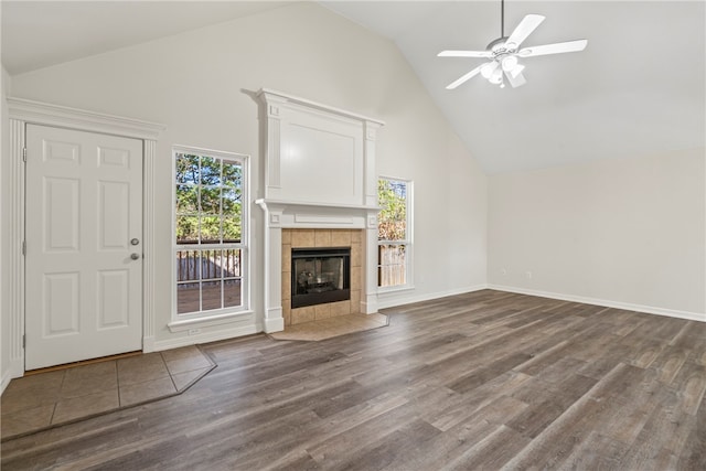 unfurnished living room with ceiling fan, a tiled fireplace, wood finished floors, and a healthy amount of sunlight