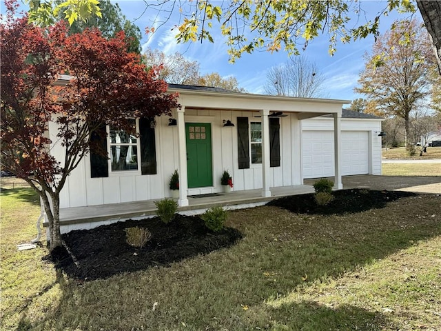 view of front facade featuring covered porch, a front yard, and a garage