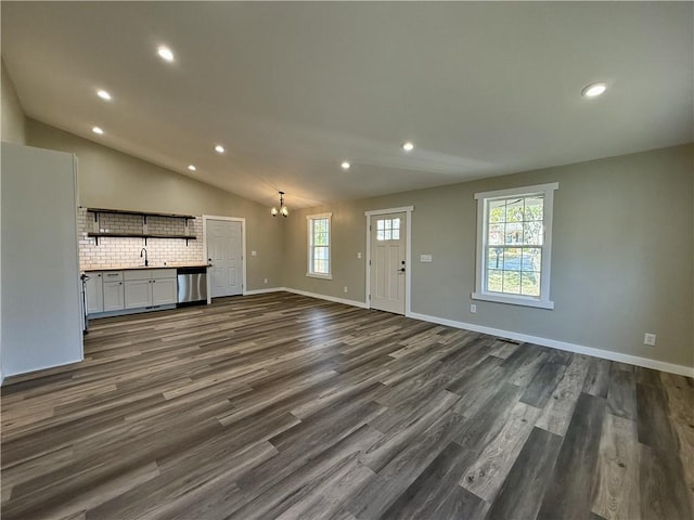 unfurnished living room with dark hardwood / wood-style flooring, vaulted ceiling, a notable chandelier, and sink