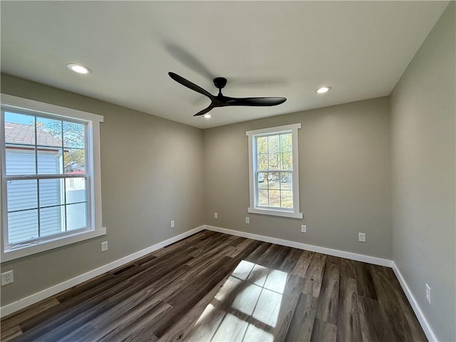 empty room featuring plenty of natural light, ceiling fan, and dark hardwood / wood-style flooring