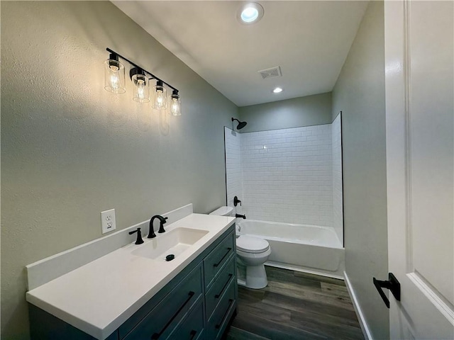 full bathroom featuring hardwood / wood-style floors, vanity, tiled shower / bath combo, and toilet