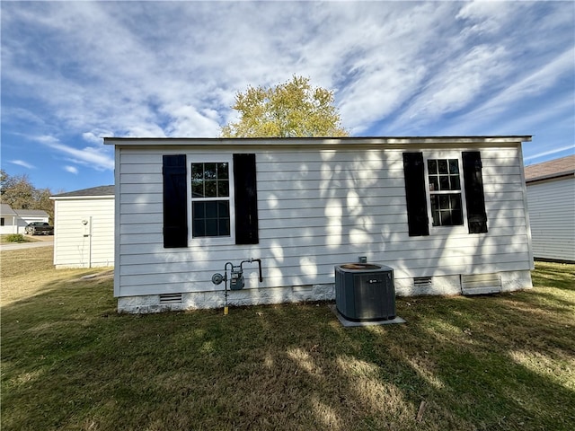 view of side of property featuring central AC unit and a lawn