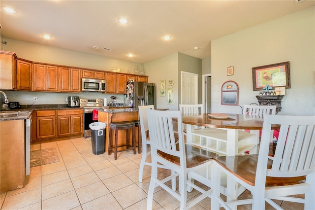 kitchen featuring sink, light tile patterned flooring, a kitchen bar, a kitchen island, and appliances with stainless steel finishes