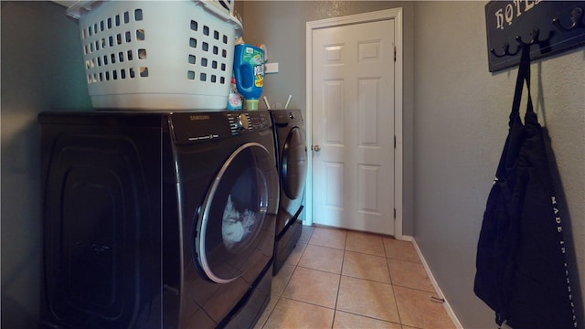 washroom featuring washing machine and dryer and light tile patterned floors