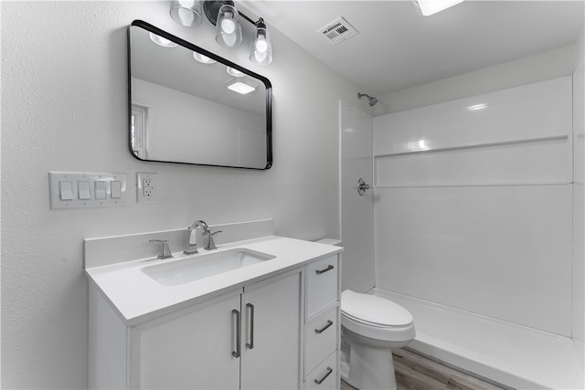 bathroom with a shower, hardwood / wood-style floors, vanity, and toilet